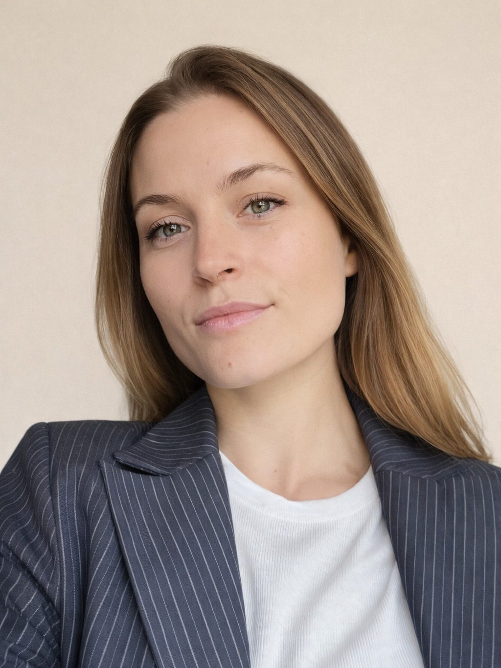Leende kvinna med brunt hår, vit t-shirt och grå kavaj.